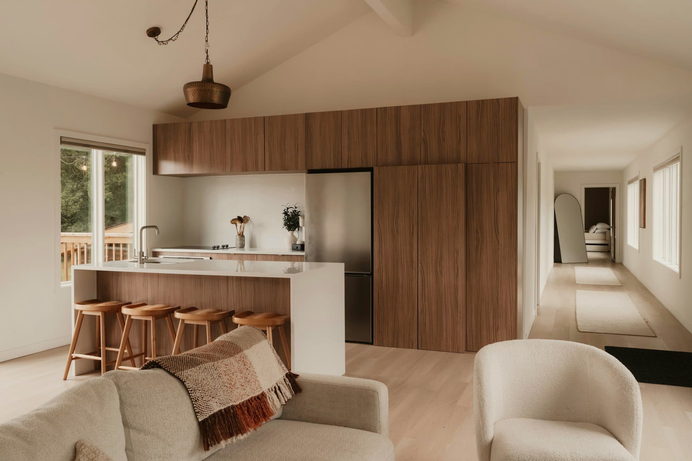 Renovated open-plan main floor with a vaulted ceiling, walnut kitchen cabinetry and a white island.